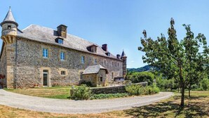 A large stone building with a tower, multiple windows, and a well-maintained lawn. - Chateau De La Falque (Saint-Geniez-d'Olt-et-d'Aubrac)