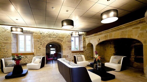 A modern lounge area with stone walls, contemporary seating, and overhead lighting. - Chateau De La Falque (Saint-Geniez-d'Olt-et-d'Aubrac)