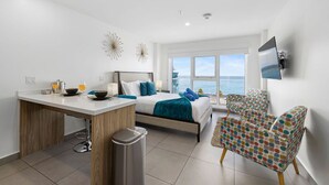 Un dormitorio moderno con cama, mesita de noche y vista al mar.