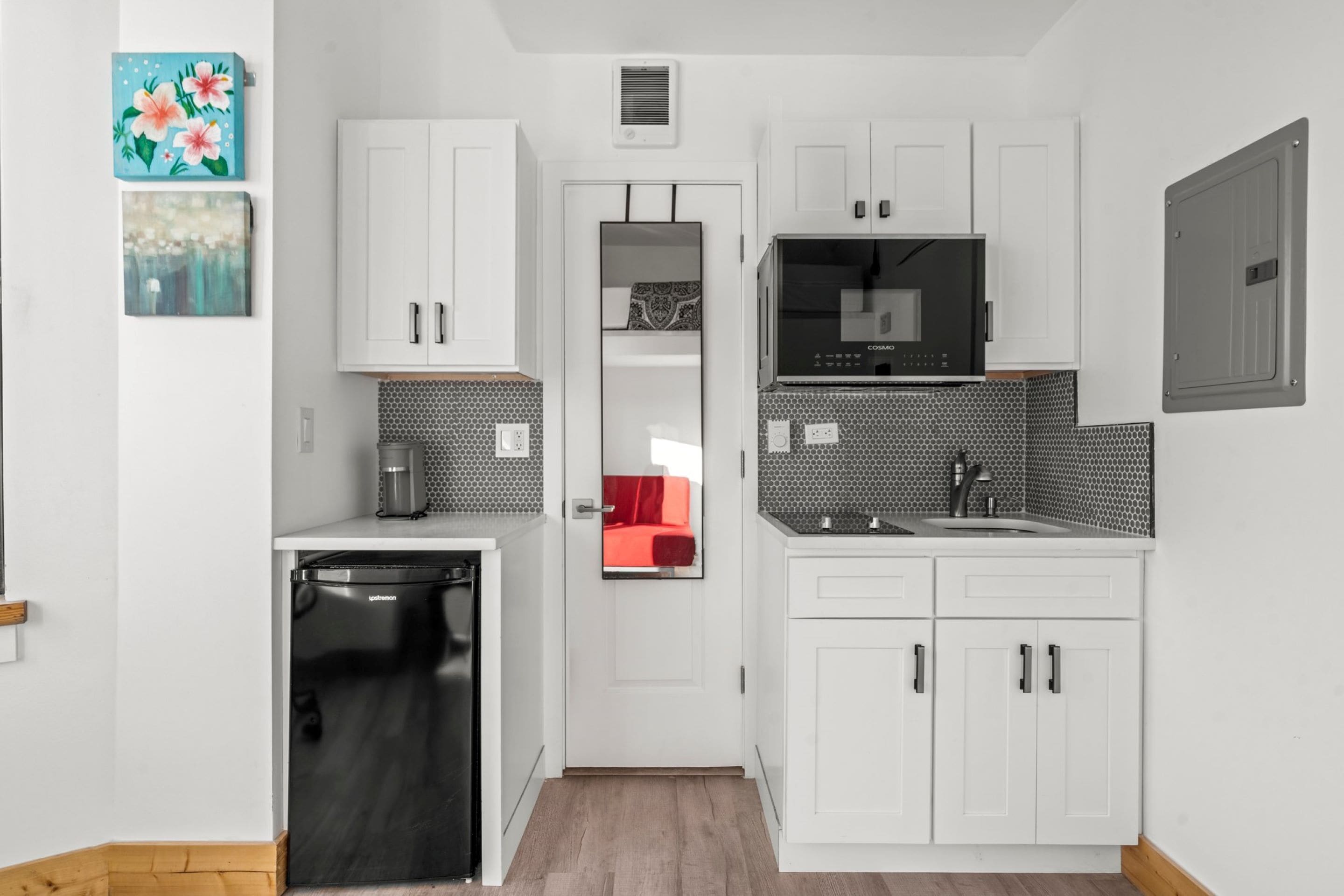 Una cocina compacta con armarios blancos, un microondas y un lavavajillas.