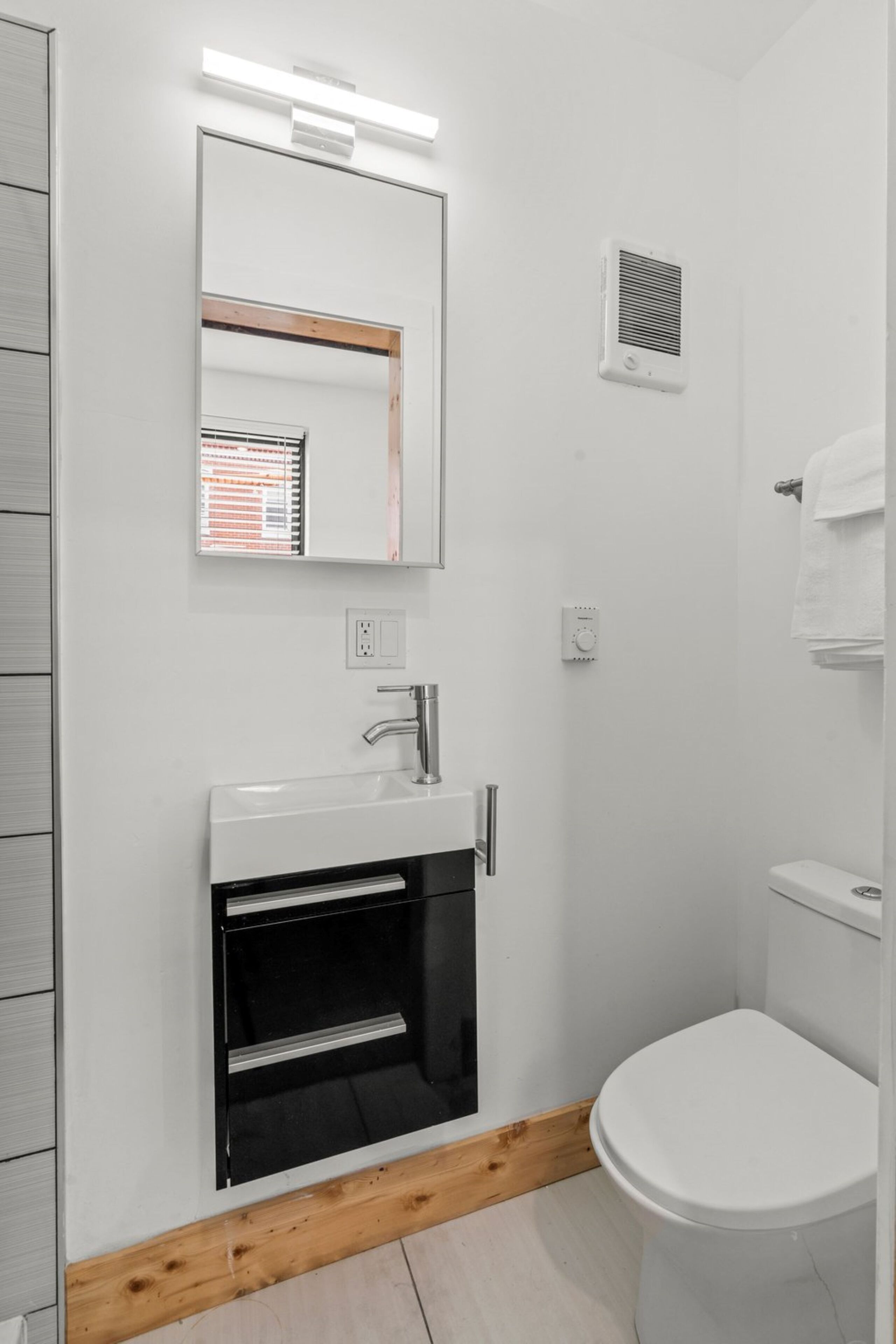 A modern bathroom with a white sink, mirror, and toilet.