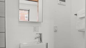 A modern bathroom with a white sink, mirror, and toilet.