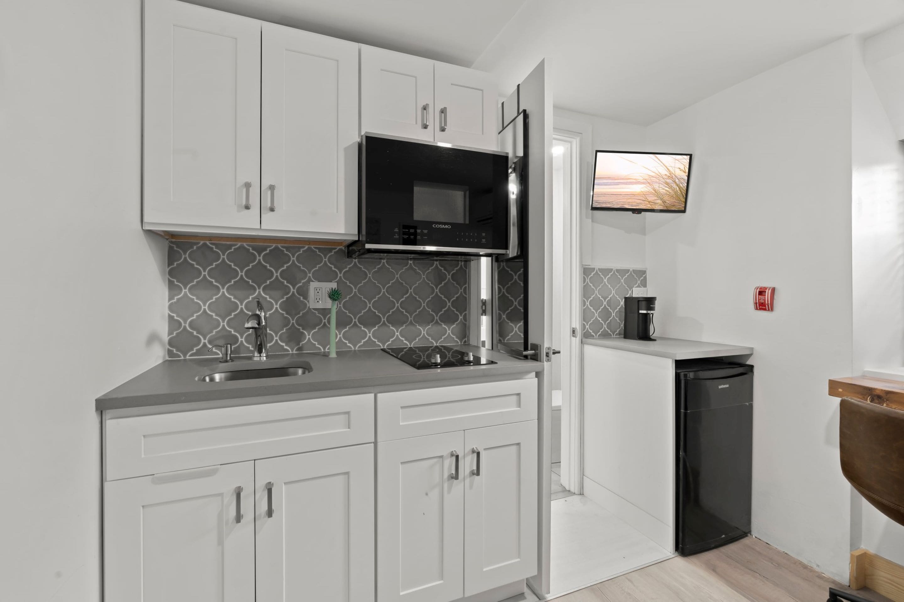 A modern kitchen with white cabinets, a black microwave, and a built-in oven.