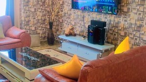 A living room with a sofa, a coffee table, a flat-screen TV mounted on the wall, and a patterned wall.