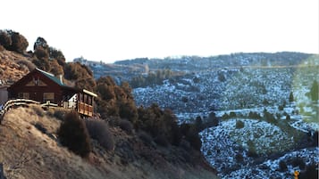 Situated on a hillside, this house offers a view of the snow-covered landscape from its wooden deck.