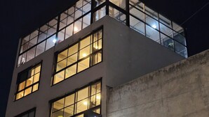A modern building with multiple windows and a glass facade at night. - HOTEL THE ROOF (León)