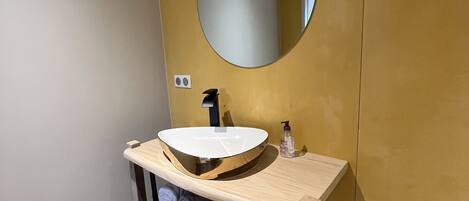 Un baño con un espejo redondo, un lavabo y un perchero para toallas.