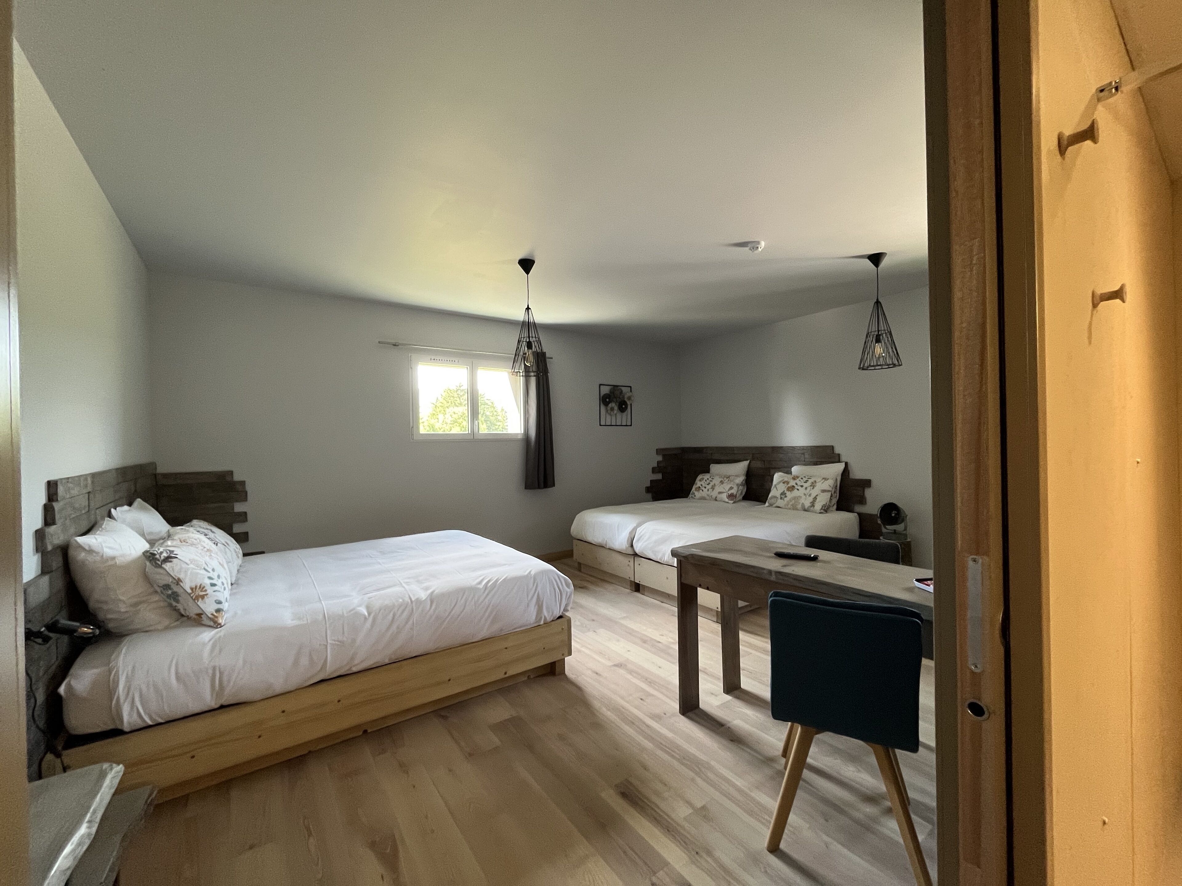 A bedroom with two beds, a wooden floor, and a desk.
