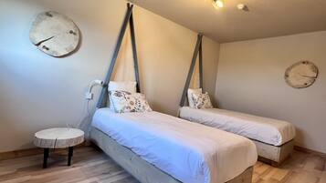 A bedroom with two beds, a small round table, and a wall clock.