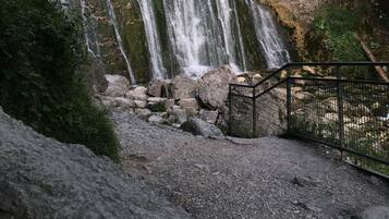 A multi-tiered waterfall with a rocky foreground and a metal railing.