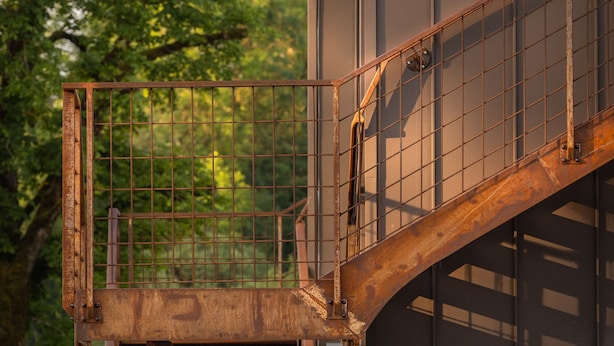 A metal staircase leading to a building with a metal door. - Hôtel En Tilleul (Pont-du-Navoy)