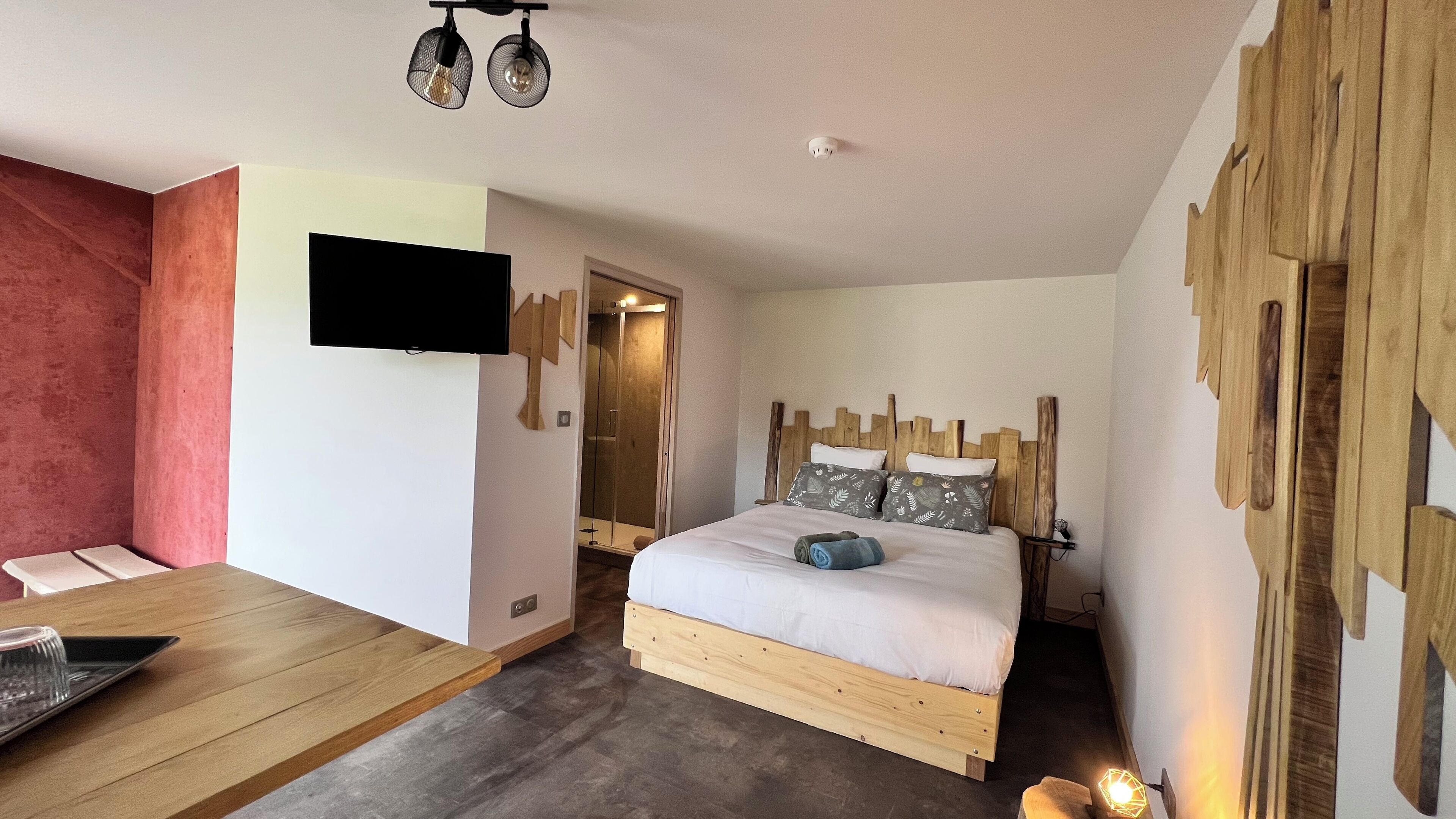 A bedroom with a wooden bed, a flat-screen TV, a wooden table, and a mirror.