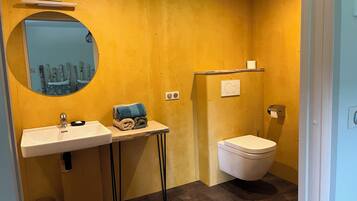 A compact bathroom with a sink, mirror, and toilet.