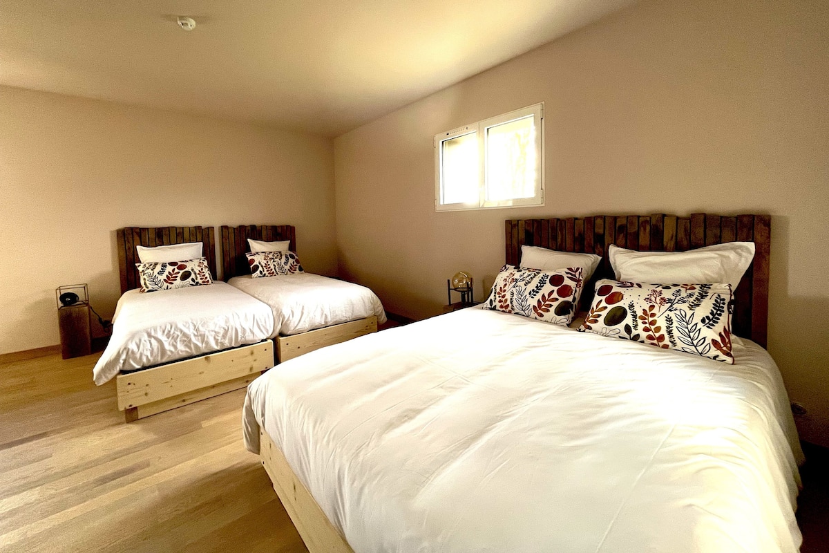 Une chambre double avec deux lits, chacun doté d’une tête de lit en bois et de linge de lit blanc.