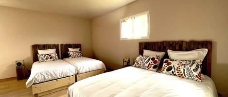 Habitación doble con dos camas, cada una con cabecero de madera y ropa de cama blanca.