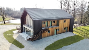 A modern two-story building with a sloped roof, large windows, and a staircase leading to an upper level. - Hôtel En Tilleul (Pont-du-Navoy)