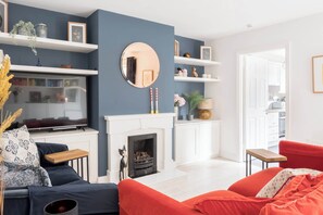 A modern living room with a fireplace, a television, and a red sofa.