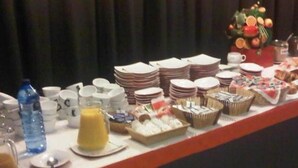 Una mesa de buffet con diversos alimentos, platos, vasos y una botella de agua.