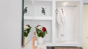 Een moderne badkamer met een witte wastafel, een spiegel, een badjas en potplanten.
