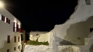 Een nachtzicht van een smalle straat met witte gebouwen en sneeuw.