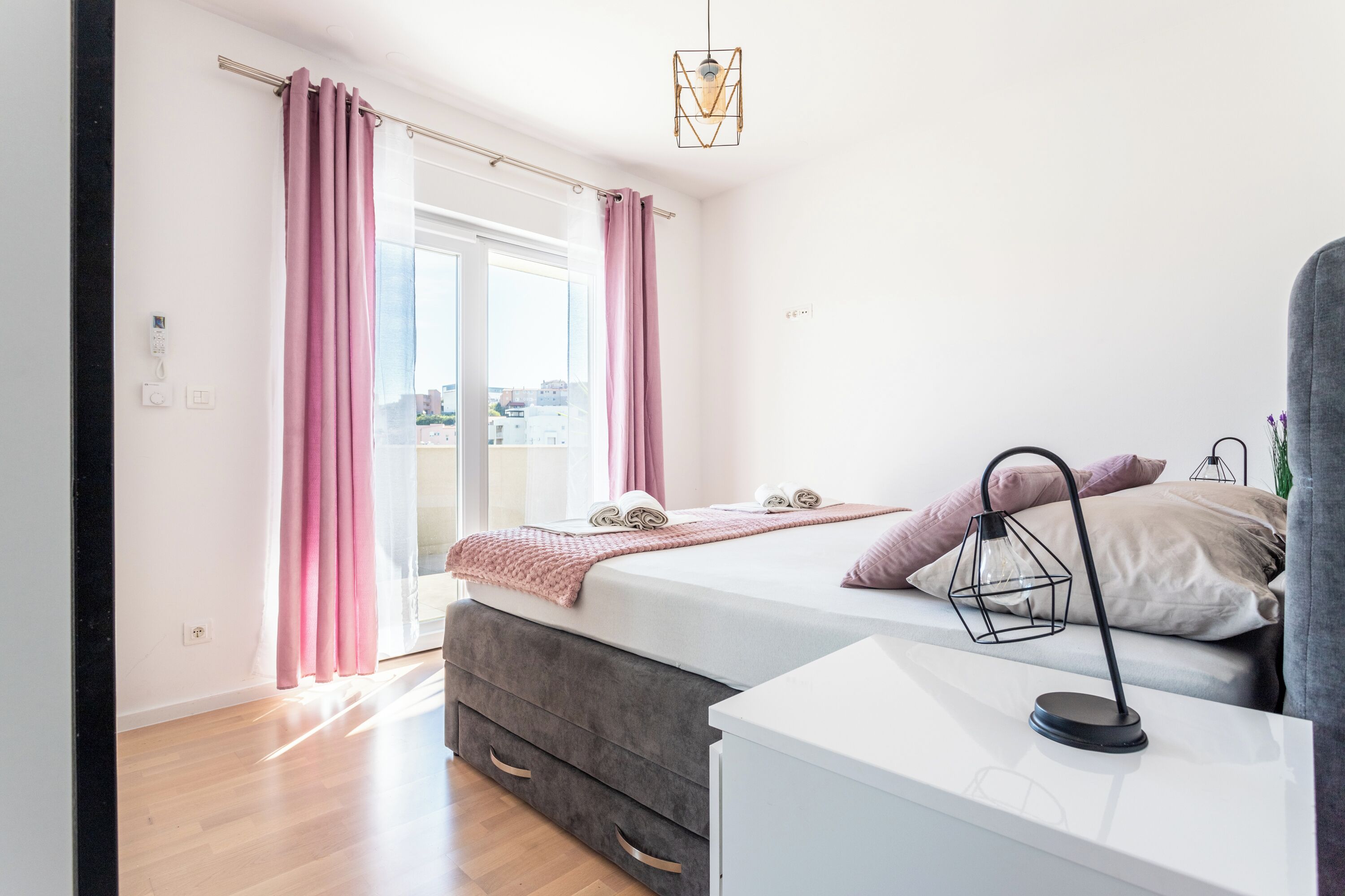Une chambre à coucher moderne avec un lit, une table de chevet et une vue sur la ville par la fenêtre.