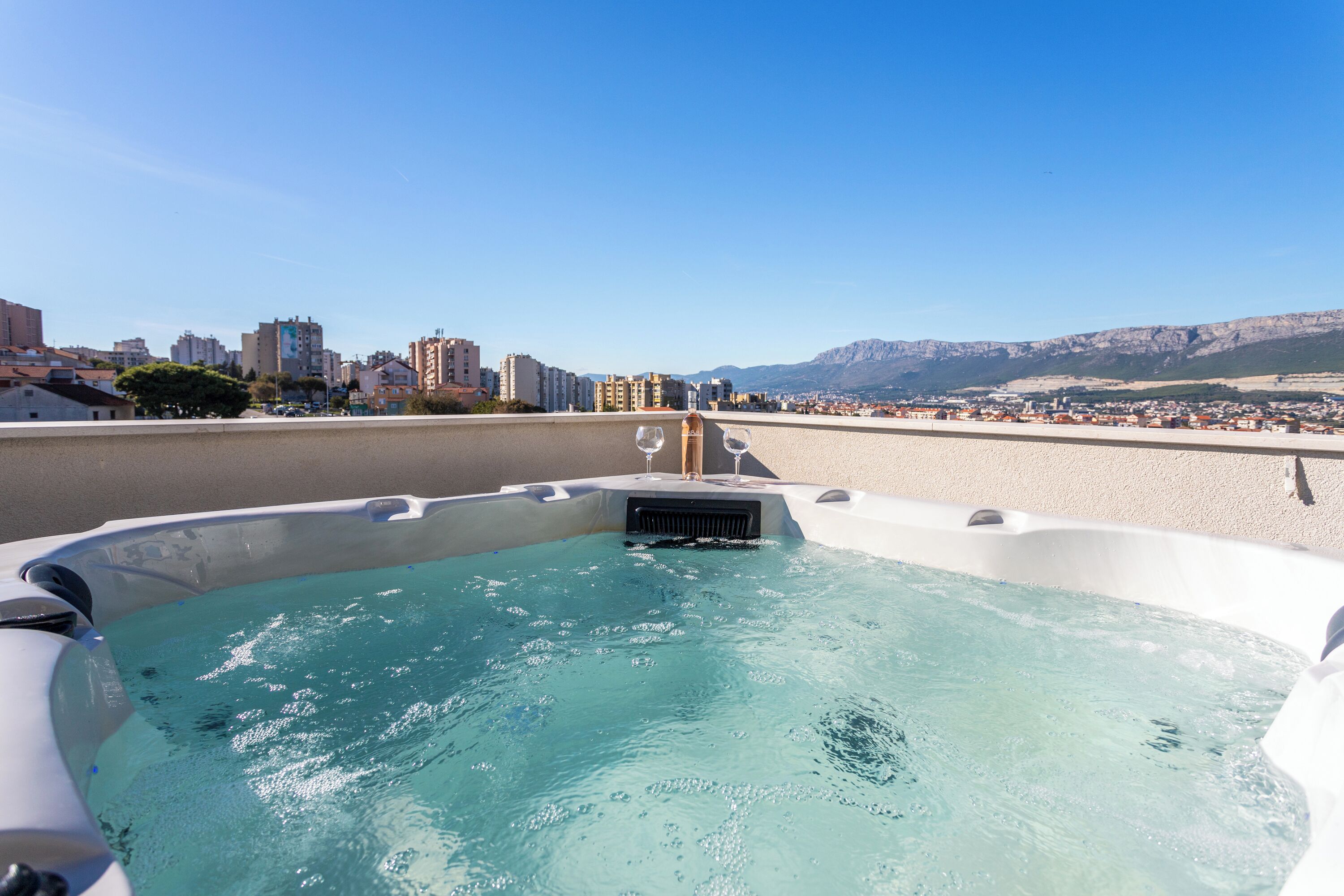 Un bain à remous avec vue sur la ville, incluant des bâtiments et des montagnes en arrière-plan.