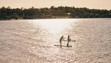 Una superficie acuática tranquila con dos personas en tablas de remo.