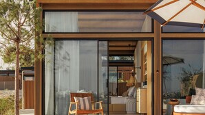 A modern house with a patio area featuring a wooden table and chairs, a sofa, and a large umbrella.