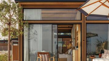 A modern house with a patio area featuring a wooden table and chairs, a sofa, and a large umbrella.