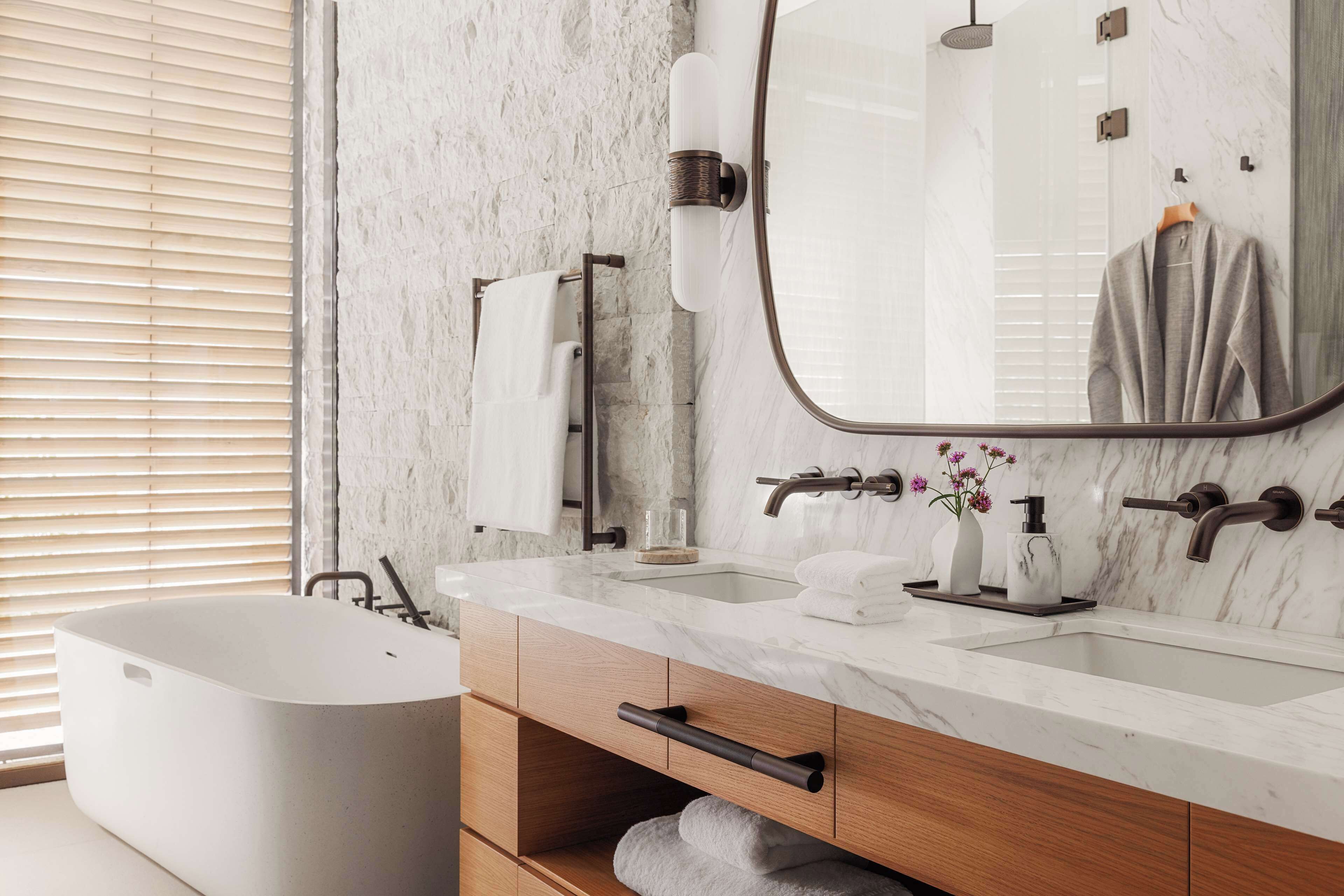 A modern bathroom with a freestanding bathtub, a marble vanity with two sinks, and a large mirror.