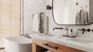 A modern bathroom with a freestanding bathtub, a marble vanity with two sinks, and a large mirror.