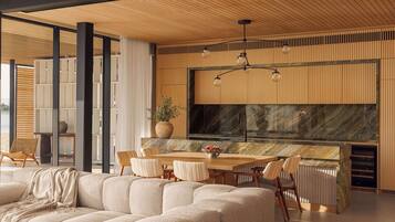 Una cocina moderna con una isla grande, techo de madera y un amplio ventanal con vistas a un paisaje urbano.