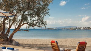 A wooden deck with two lounge chairs and a small table, overlooking a beach and the sea. - One&Only Aesthesis (Glyfada)