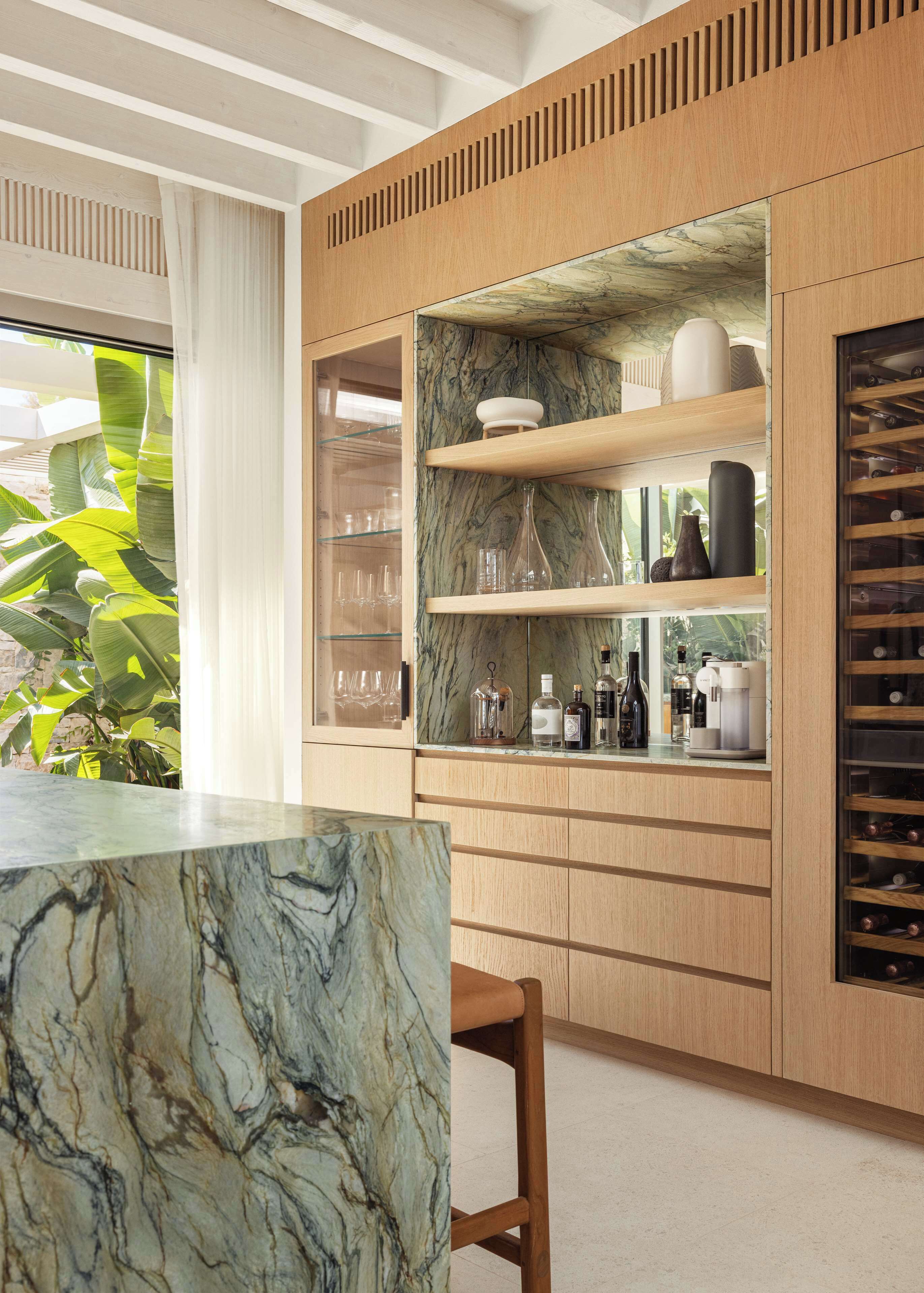 A modern kitchen with marble countertops, wooden cabinets, and a built-in wine rack.
