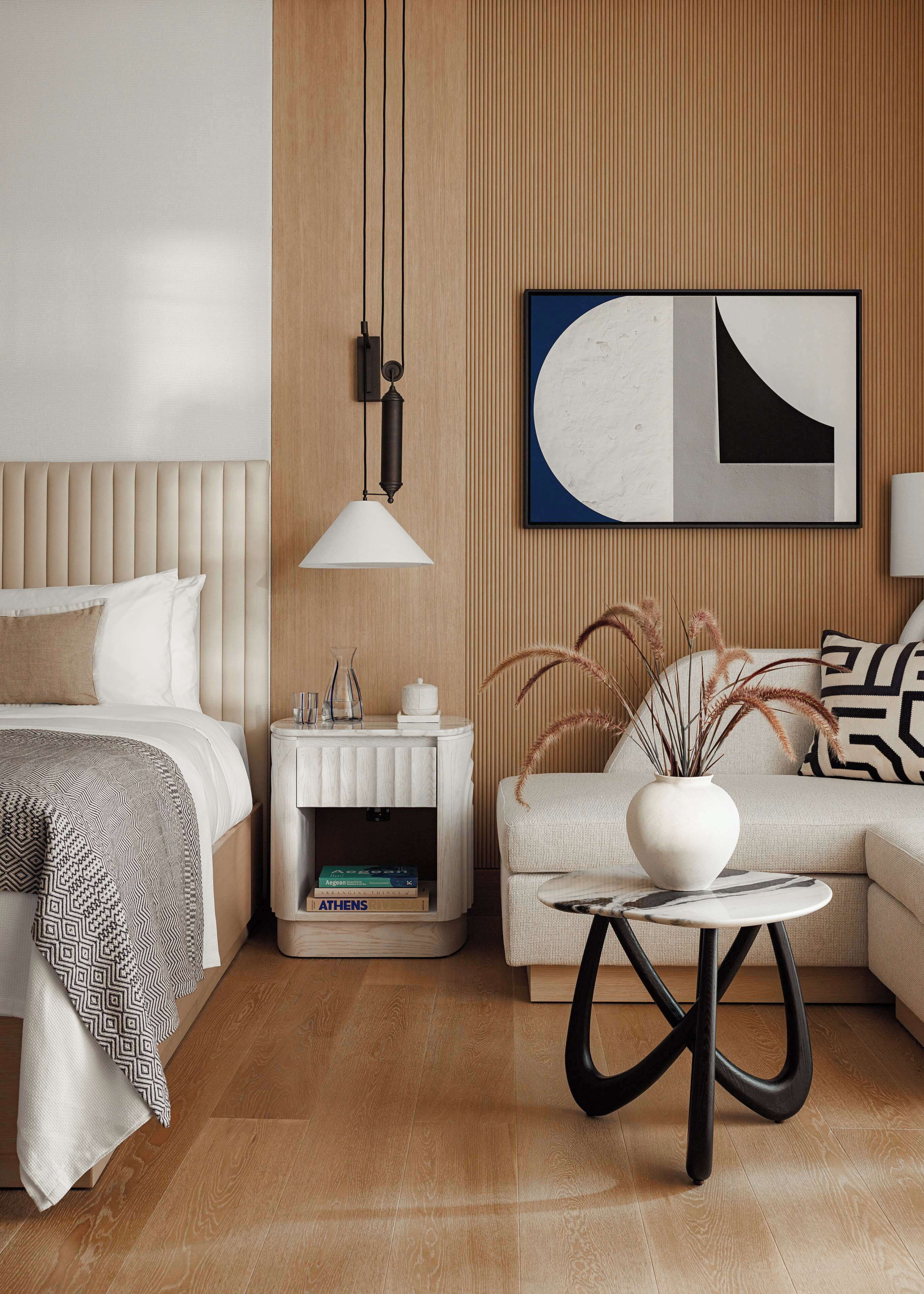 Un dormitorio moderno con cama, mesita de noche, lámpara y una obra de arte colgada en la pared.