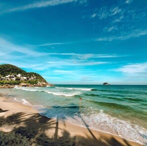 A beach with clear blue water, a sandy shore, and a small island in the distance. - Pousada Favo de Mel Pernambuco (Guarujá)