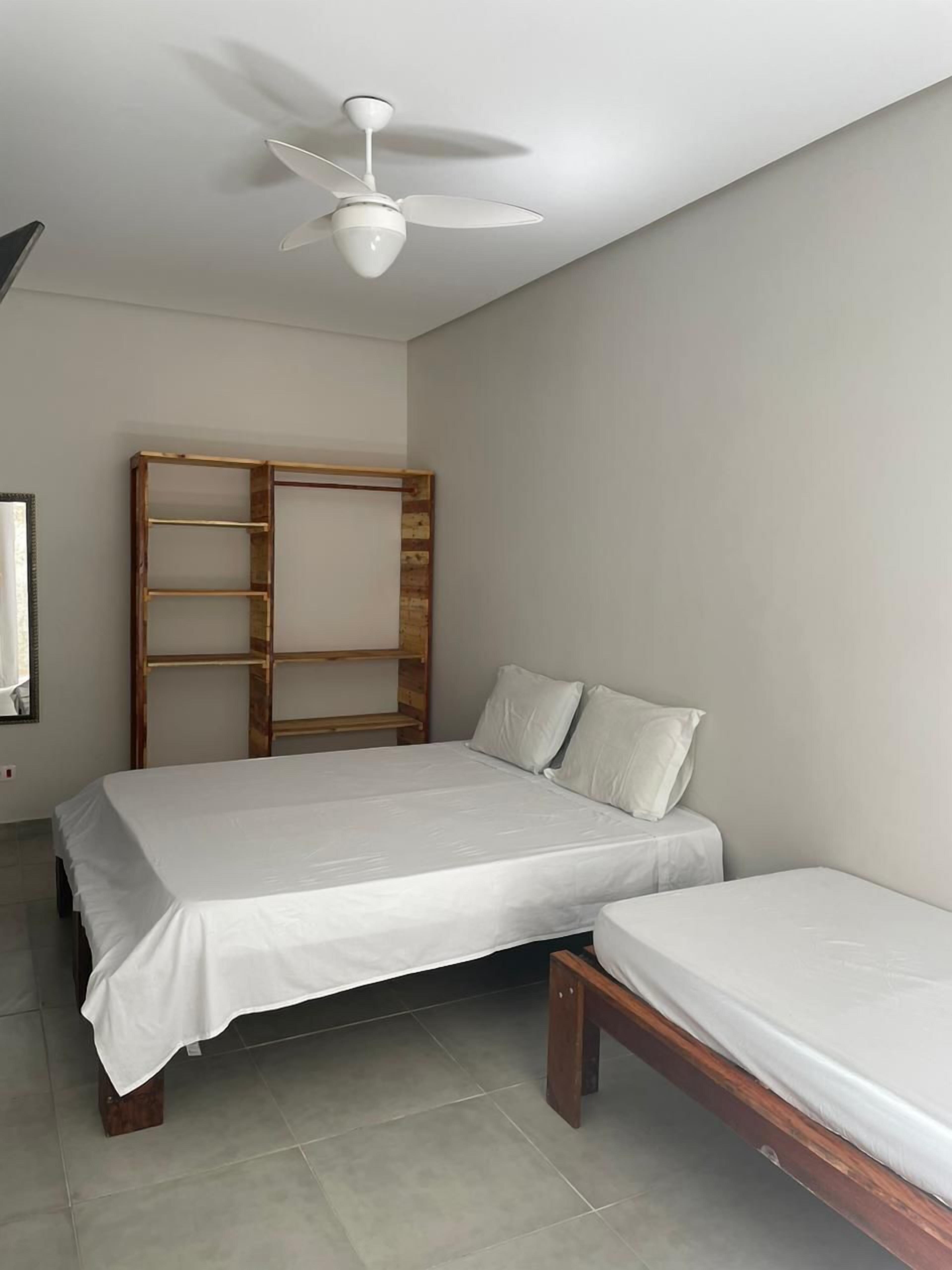 Un dormitorio con cama, un banco y un ventilador de techo.