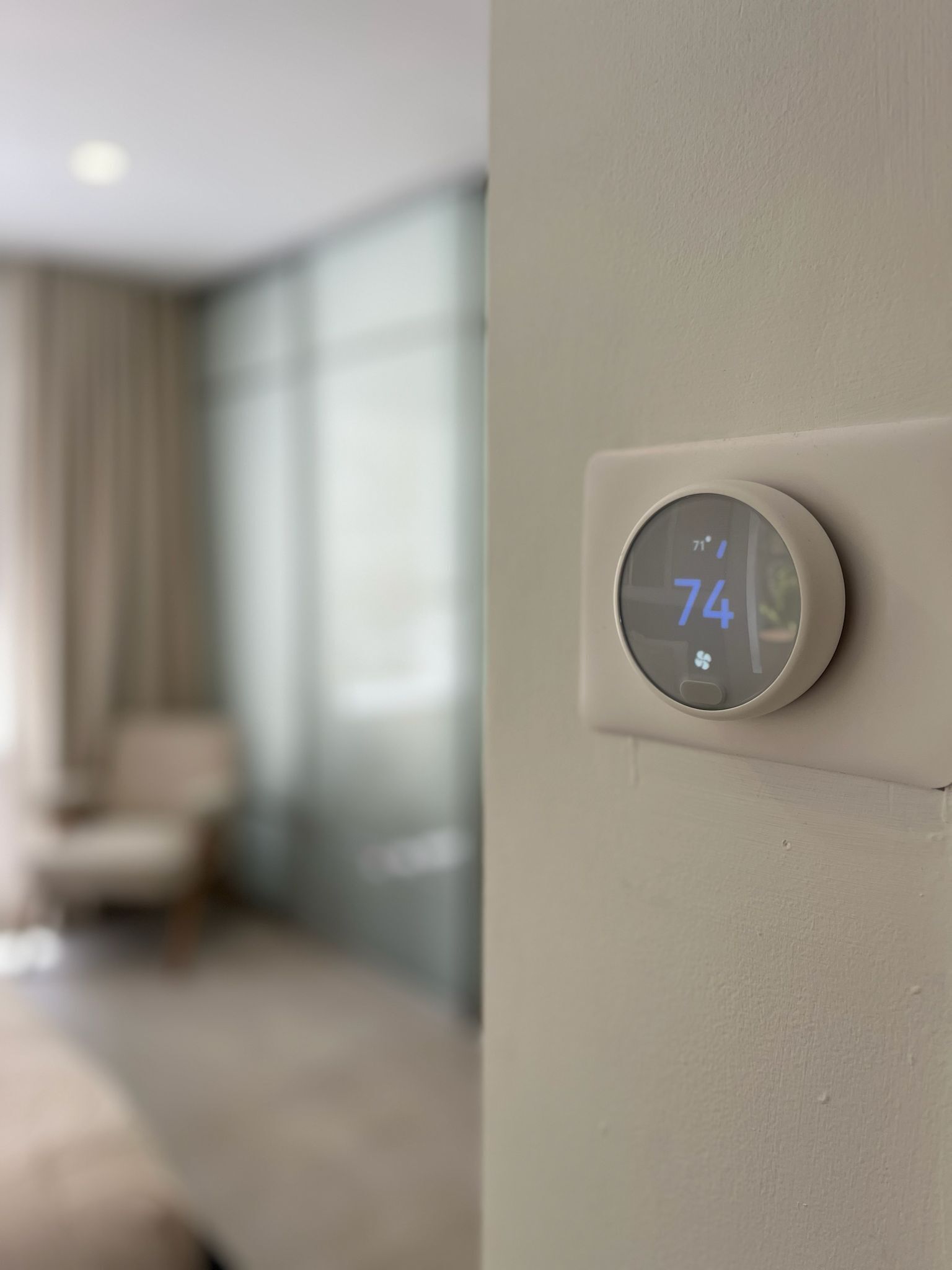 A thermostat on a wall displaying a temperature of 74 degrees.
