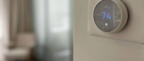 A thermostat on a wall displaying a temperature of 74 degrees.