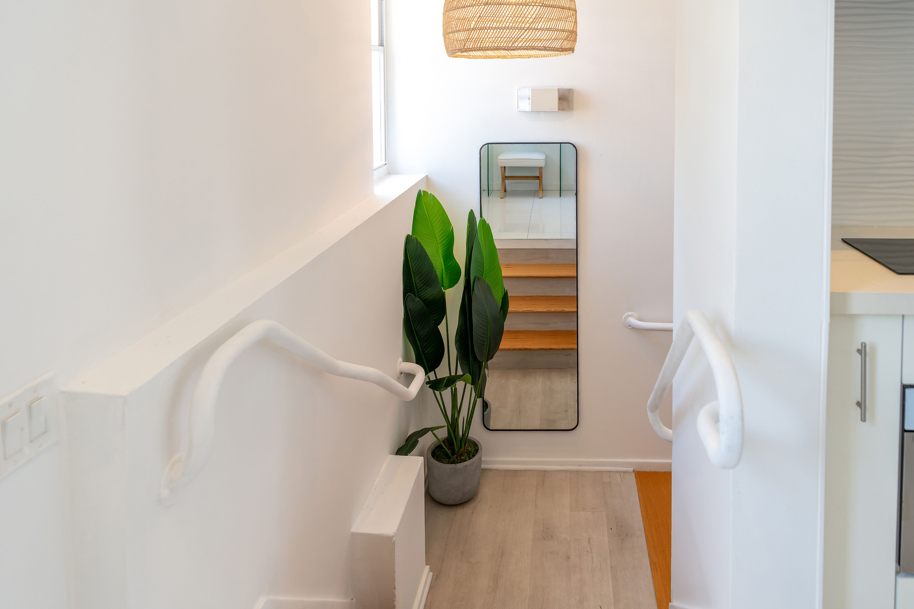 Eine moderne Treppe mit einem Blumentopf, einem Spiegel und einer Leuchte.