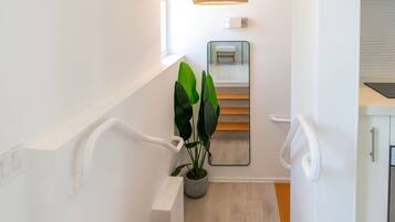 Eine moderne Treppe mit einem Blumentopf, einem Spiegel und einer Leuchte.