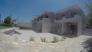 A modern two-story building with a stone-paved entrance and a small garden area. - Yianna Studios (Rhodes)