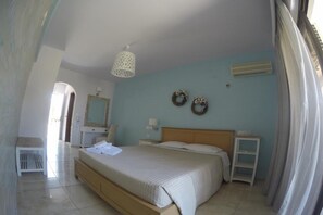 A bedroom with a bed, bedside tables, a mirror, and a wall-mounted air conditioner. - Yianna Studios (Rhodes)