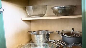 A kitchen with a green cabinet, a metal colander, a glass baking dish, and a pot.