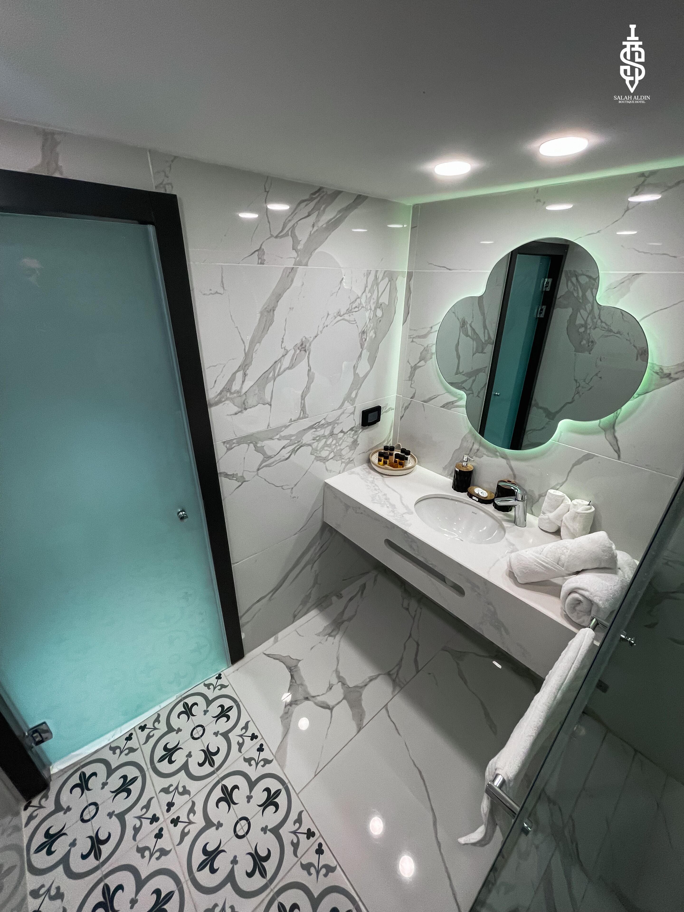 A modern bathroom with a marble backsplash, a glass shower enclosure, and a vanity with a mirror.