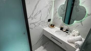 A modern bathroom with a marble backsplash, a glass shower enclosure, and a vanity with a mirror.