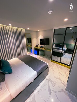 A modern hotel room with a large bed, a desk with a computer, a mirror, and a sliding glass door to a balcony. - Saladin Boutique Hotel (Jerusalem)