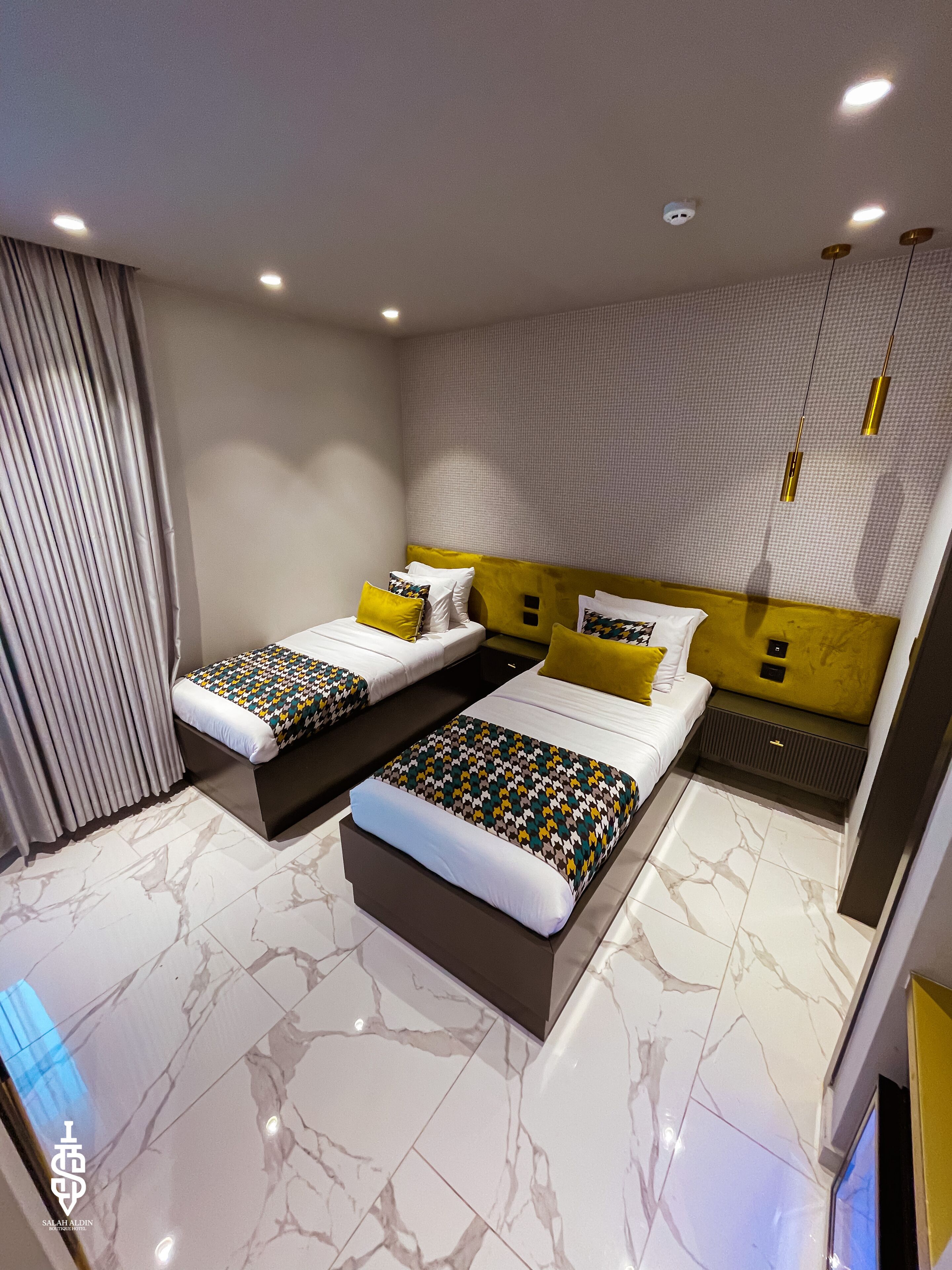 A modern bedroom with two beds, marble flooring, and a patterned wall.