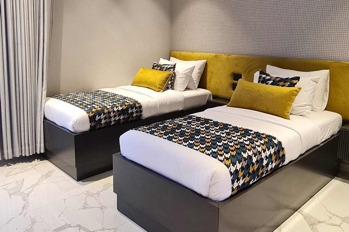 Une chambre d’hôtel moderne avec deux lits, une tête de lit et une couvre-lit à motifs.