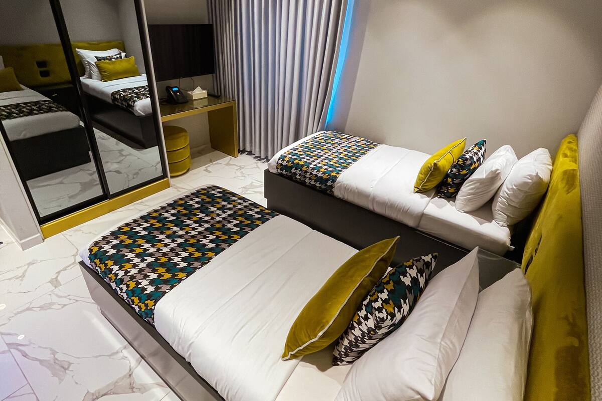 Une chambre d’hôtel moderne équipée d’un grand lit, d’un canapé-lit séparé, d’un bureau et d’un miroir.